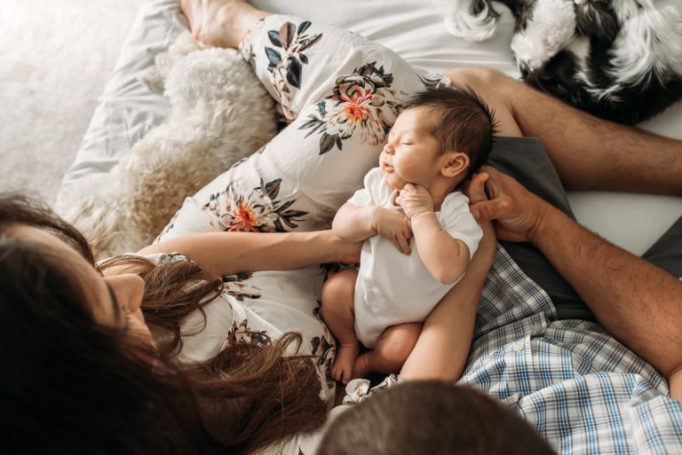 mom and dad holding newborn baby boy in their home baby photo session